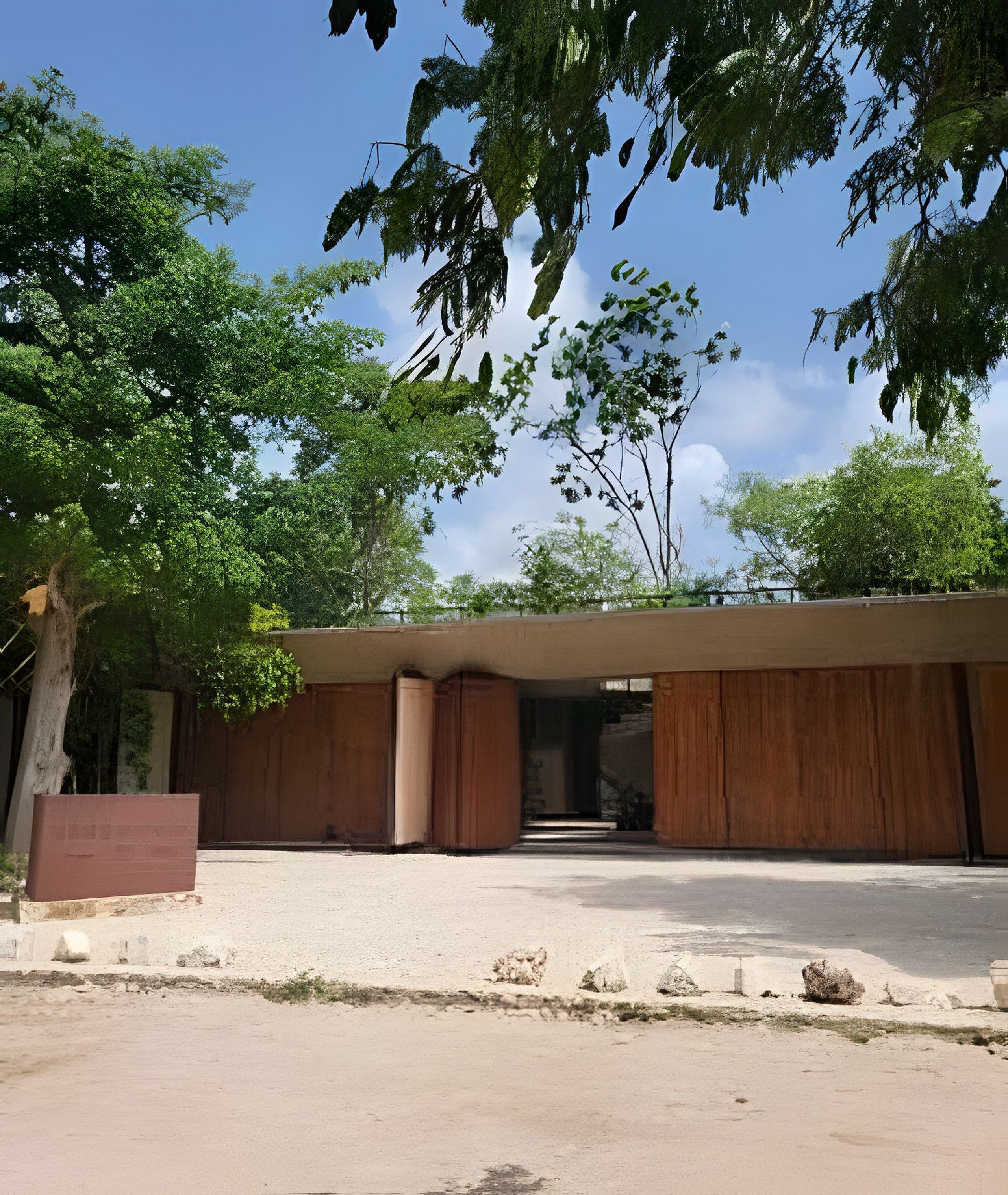 A building with a flat roof, large windows, and a concrete ground.