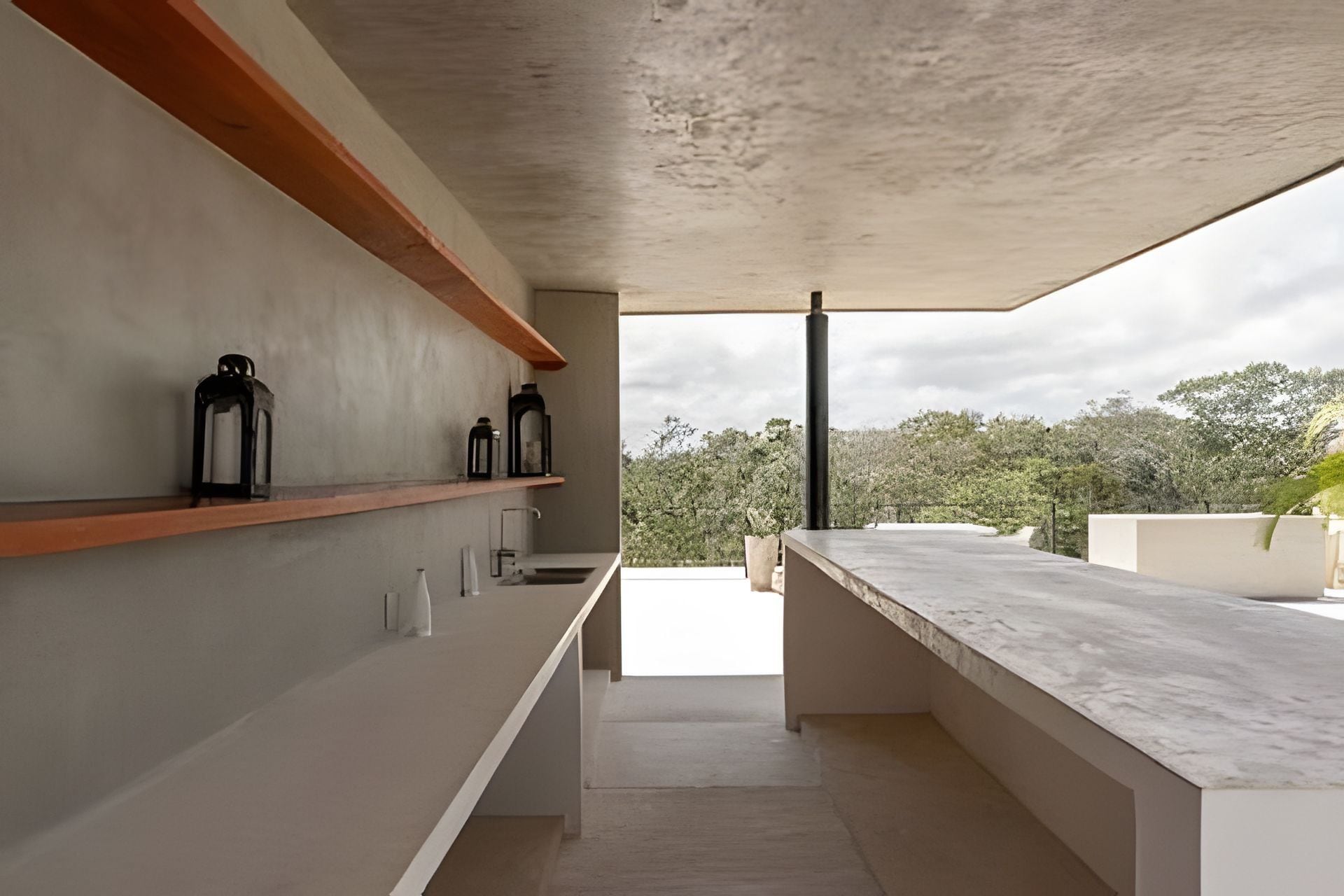 Una cocina moderna con encimera de mármol, estanterías de madera y vistas a árboles.