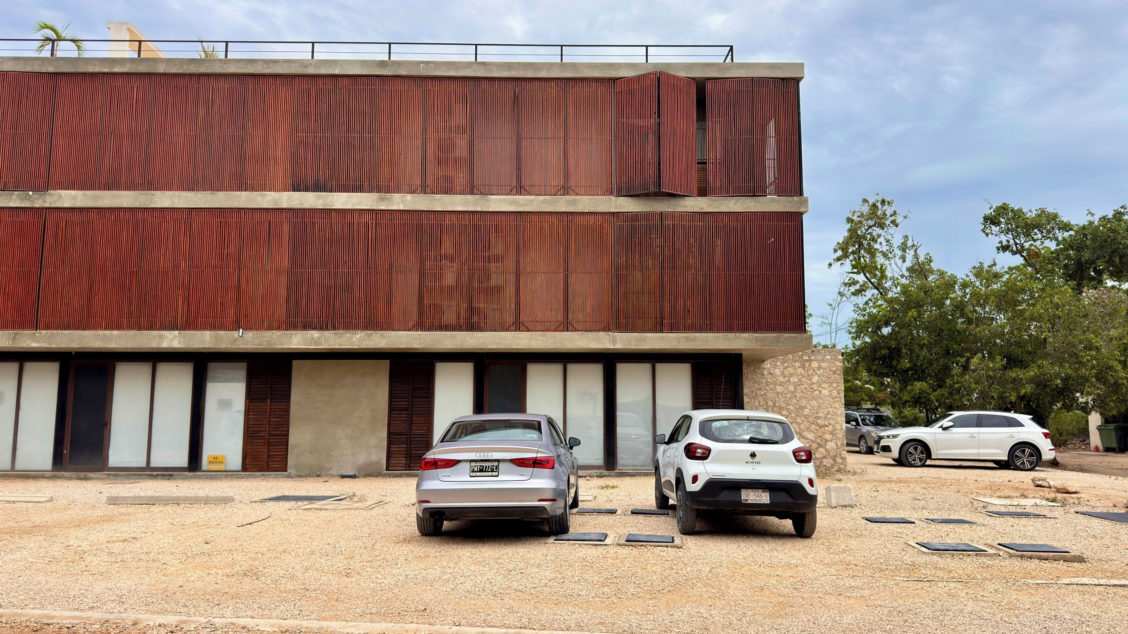 A modern building with a two-story structure, featuring a flat roof and a series of vertical slats on the facade.
