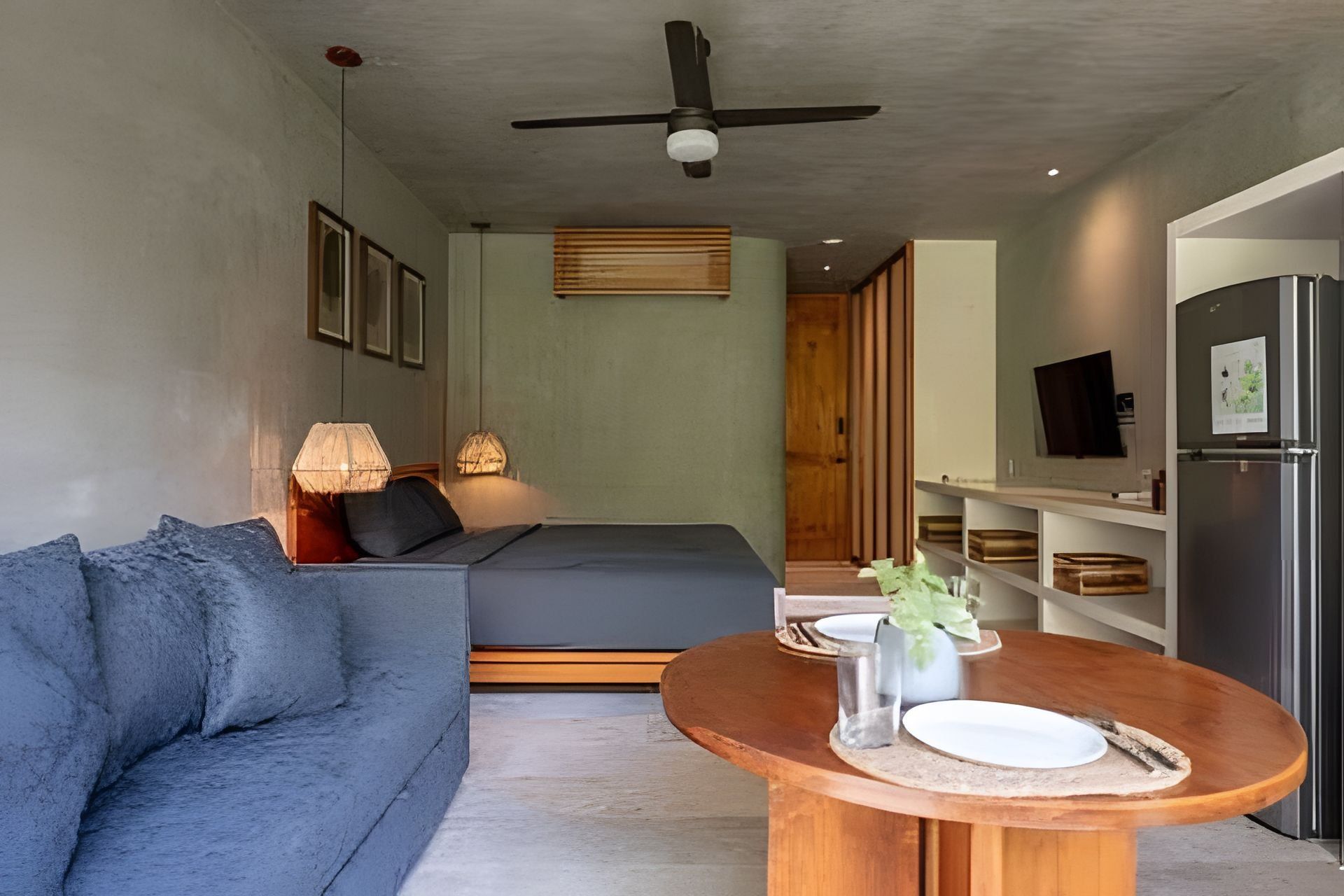 Ein modernes Schlafzimmer mit einem Bett, einer Couch, einem Esstisch und einem Kühlschrank.