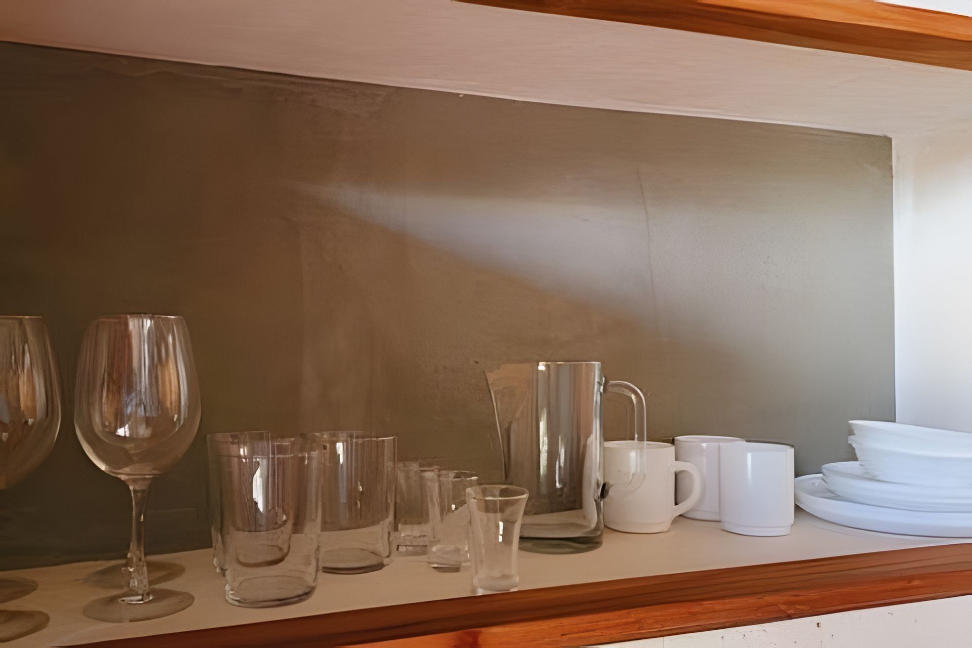 Una encimera de cocina con varios vasos y vajilla de cerámica blanca.