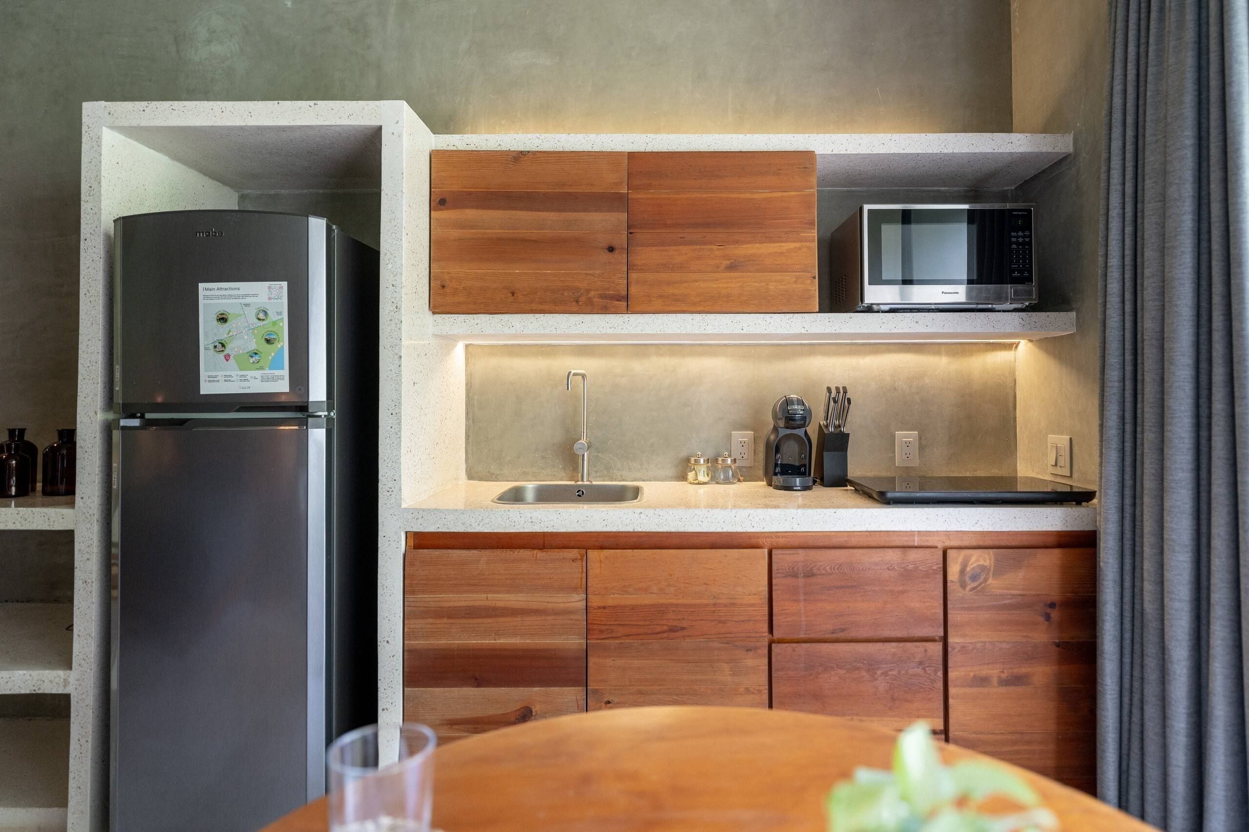 A compact kitchen with a built-in refrigerator, a microwave, and wooden cabinetry.