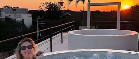 A person in a hot tub with a sunset in the background.