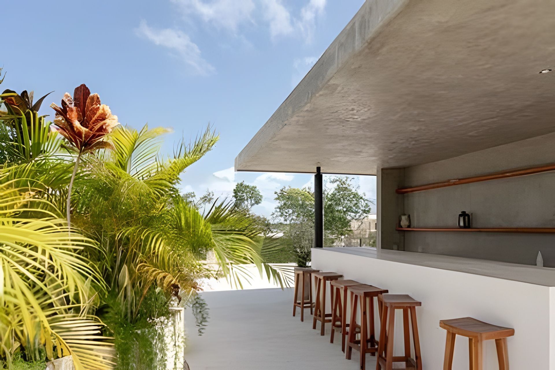 Un área de bar exterior moderna con taburetes de madera y una estructura de hormigón.