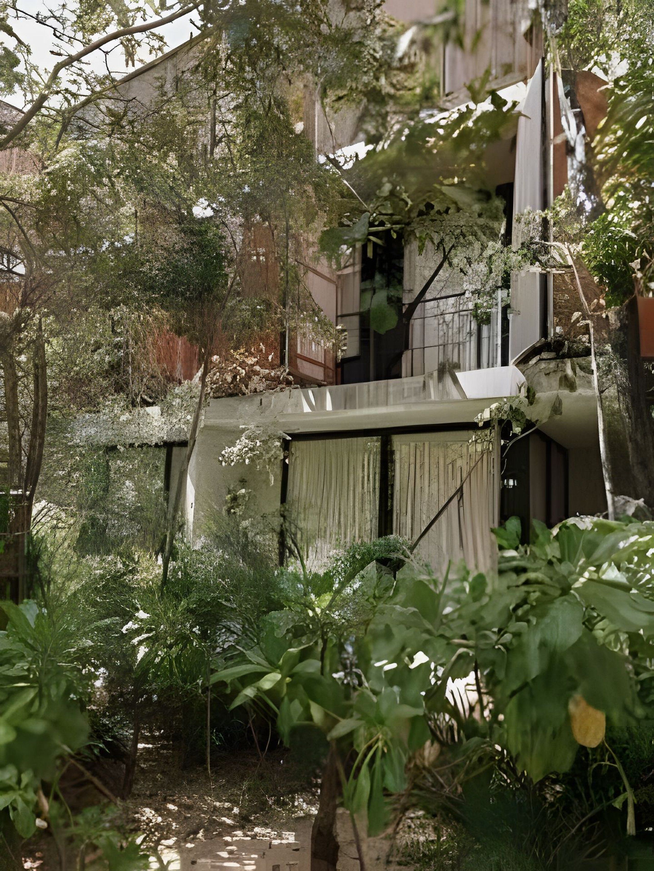 Un bâtiment doté d’un balcon, entouré d’une végétation luxuriante et d’une structure en béton.