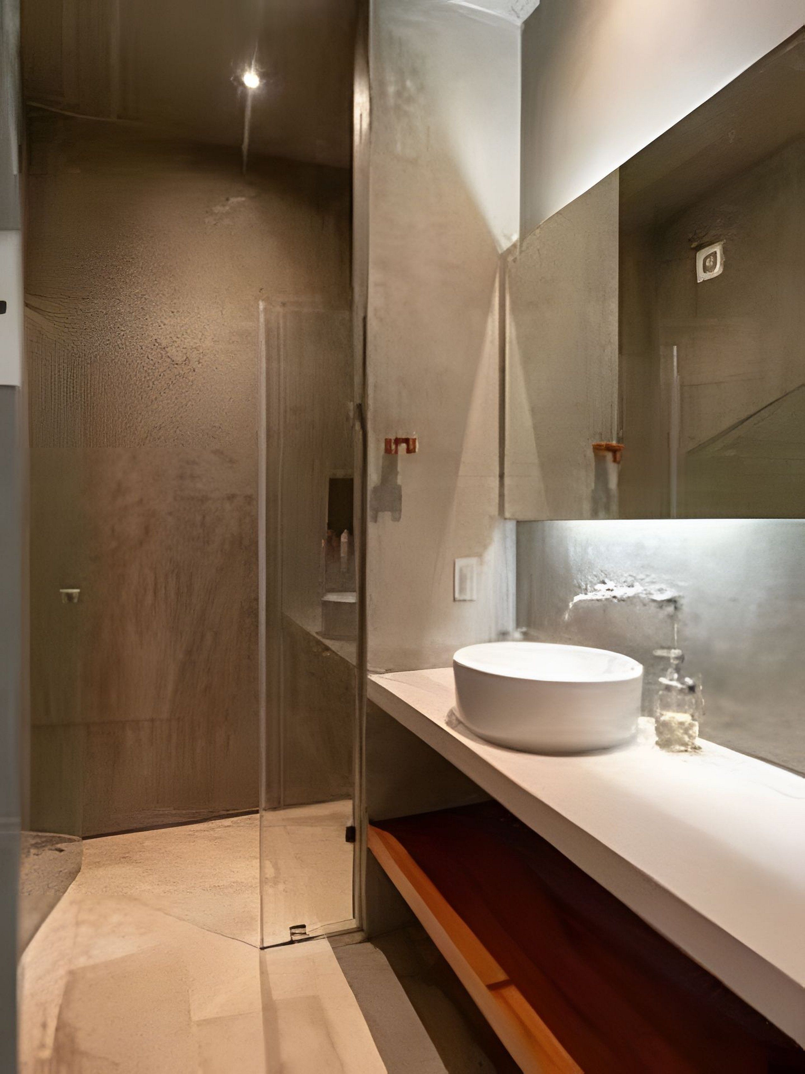 Une salle de bain moderne avec une douche à parois de verre, un lavabo blanc et un grand miroir.