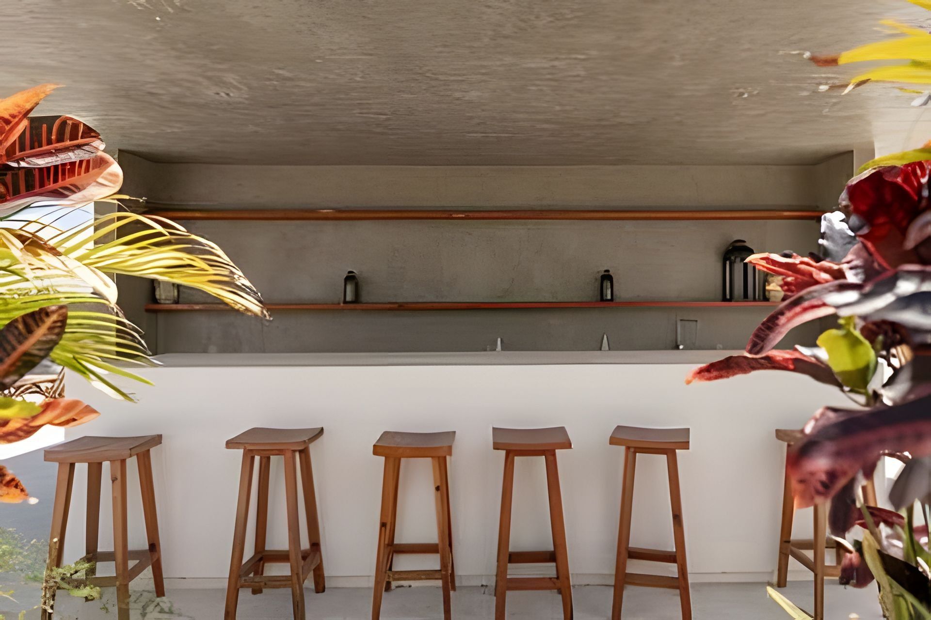 Una cocina moderna con techo de hormigón, taburetes de madera y una zona de bar con estanterías.