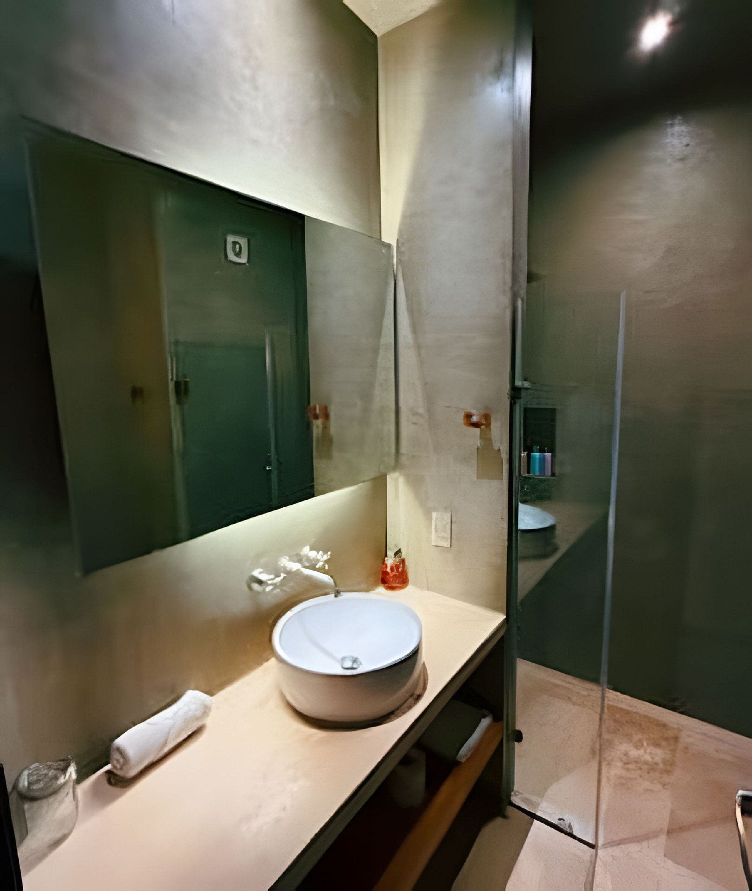 A modern bathroom with a round sink, a large mirror, and a glass shower enclosure.