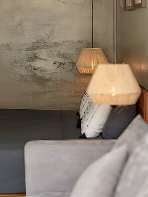 Een kamer met een grijze bank, een lamp en een gestructureerde wand.