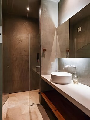 Een moderne badkamer met een glazen douchecabine, een witte wastafel en een grote spiegel.