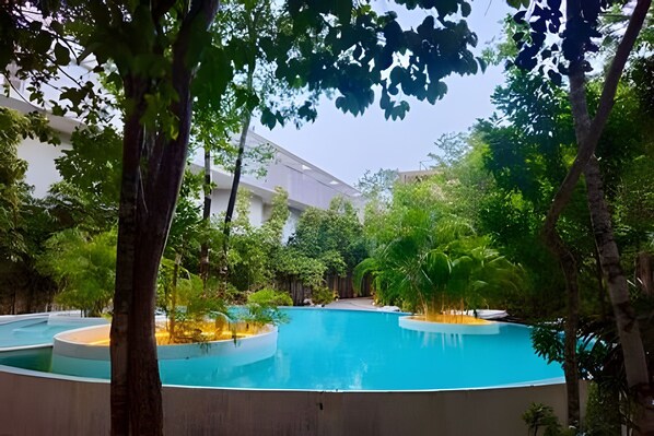 Une piscine entourée d’arbres et un bâtiment doté d’un toit plat.
