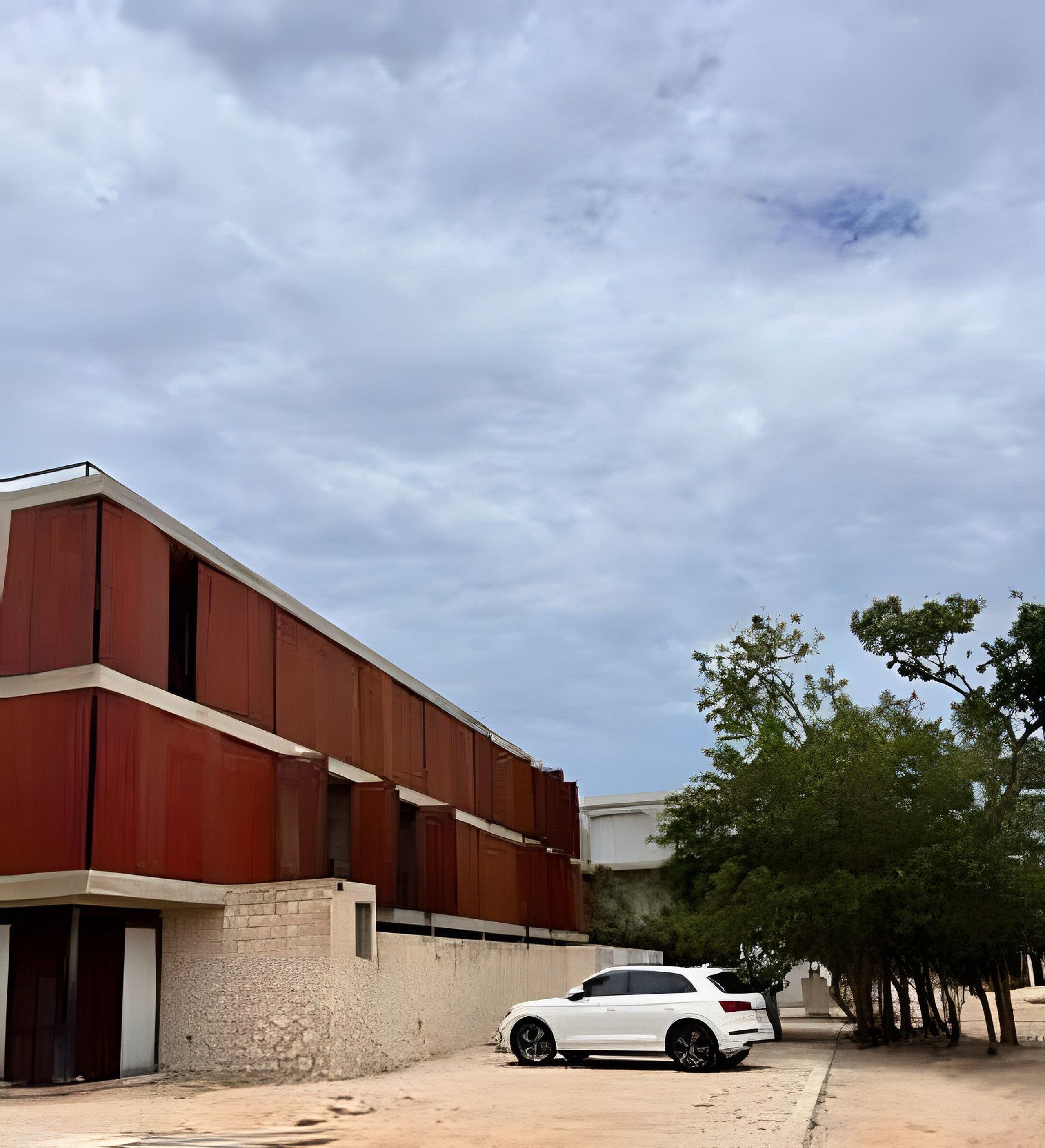A white car parked in front of a red building with a clear sky.