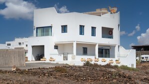 Un bâtiment moderne de couleur blanche, doté de nombreuses fenêtres, d’un balcon et d’une bouée de sauvetage sur le toit.