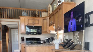 Une cuisine moderne avec des meubles en bois, un four à micro-ondes encastré et un grand écran de télévision.