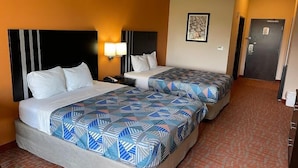 Una habitación de hotel con dos camas, cada una con una colcha estampada, una mesita de noche con una lámpara y un cuadro en la pared.