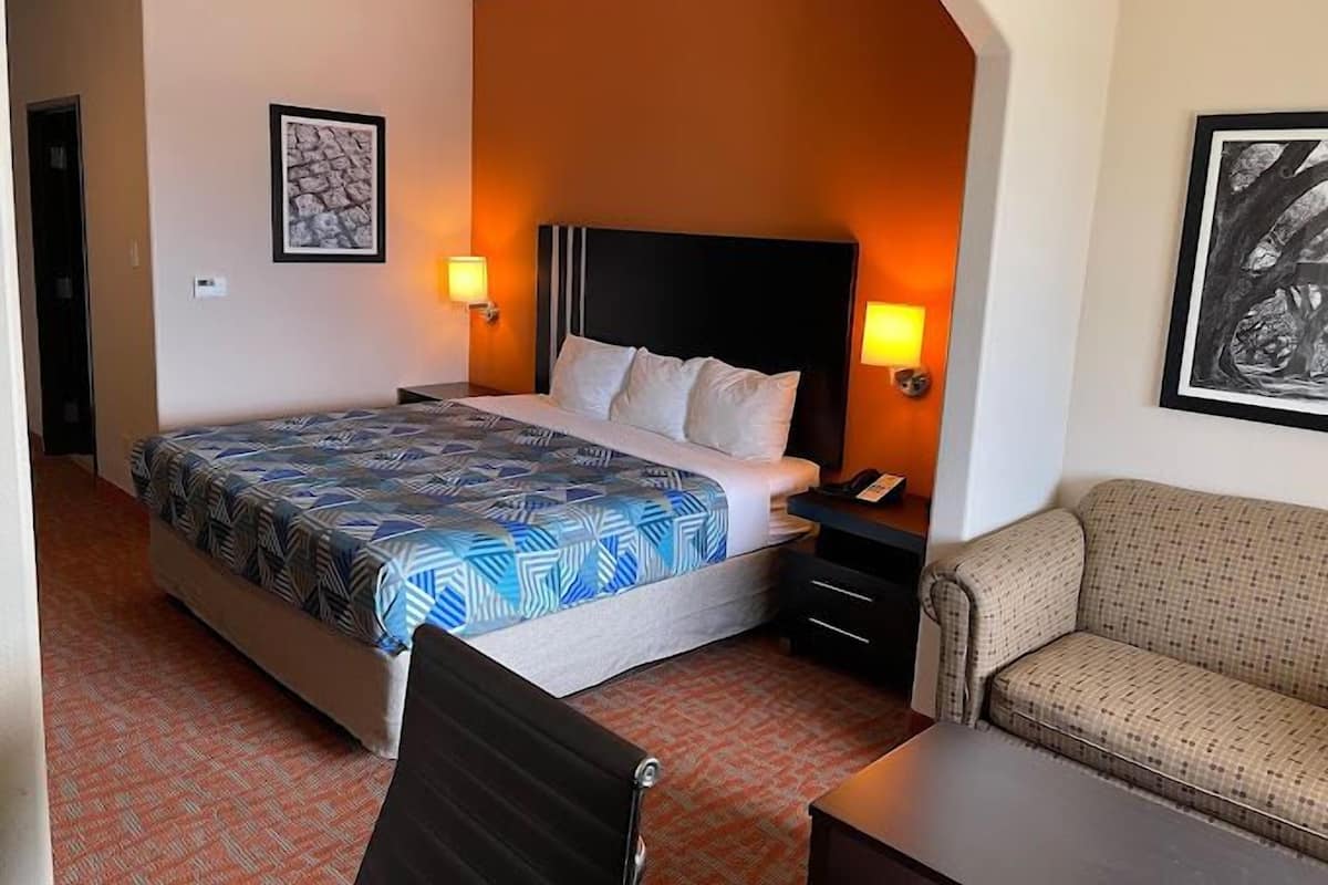 Ein Hotelzimmer mit einem Bett, zwei Nachttischen, einem Sessel und einem Sofa.