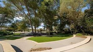 A landscaped area with a curved pathway, a small lawn, and trees. - Self Contained Granny Flat with Play Space (Alkimos)