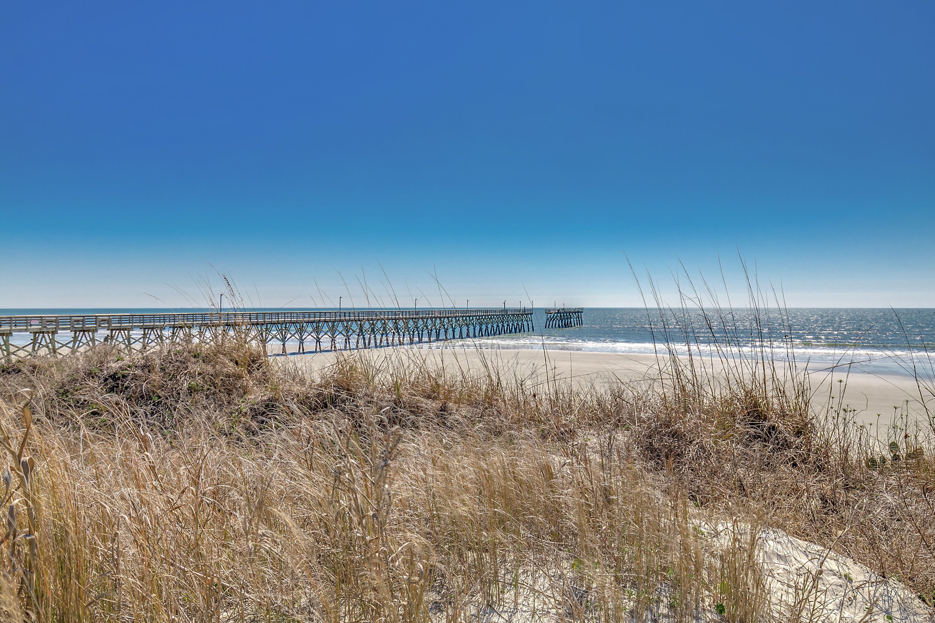 A beach with a pier extending into the ocean.