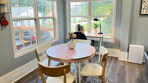 A dining area with a round table, two chairs, a vase with flowers, and a window with a view of the outside. - Lovely Pet Frendly Home by Sherman (Boiling Springs)
