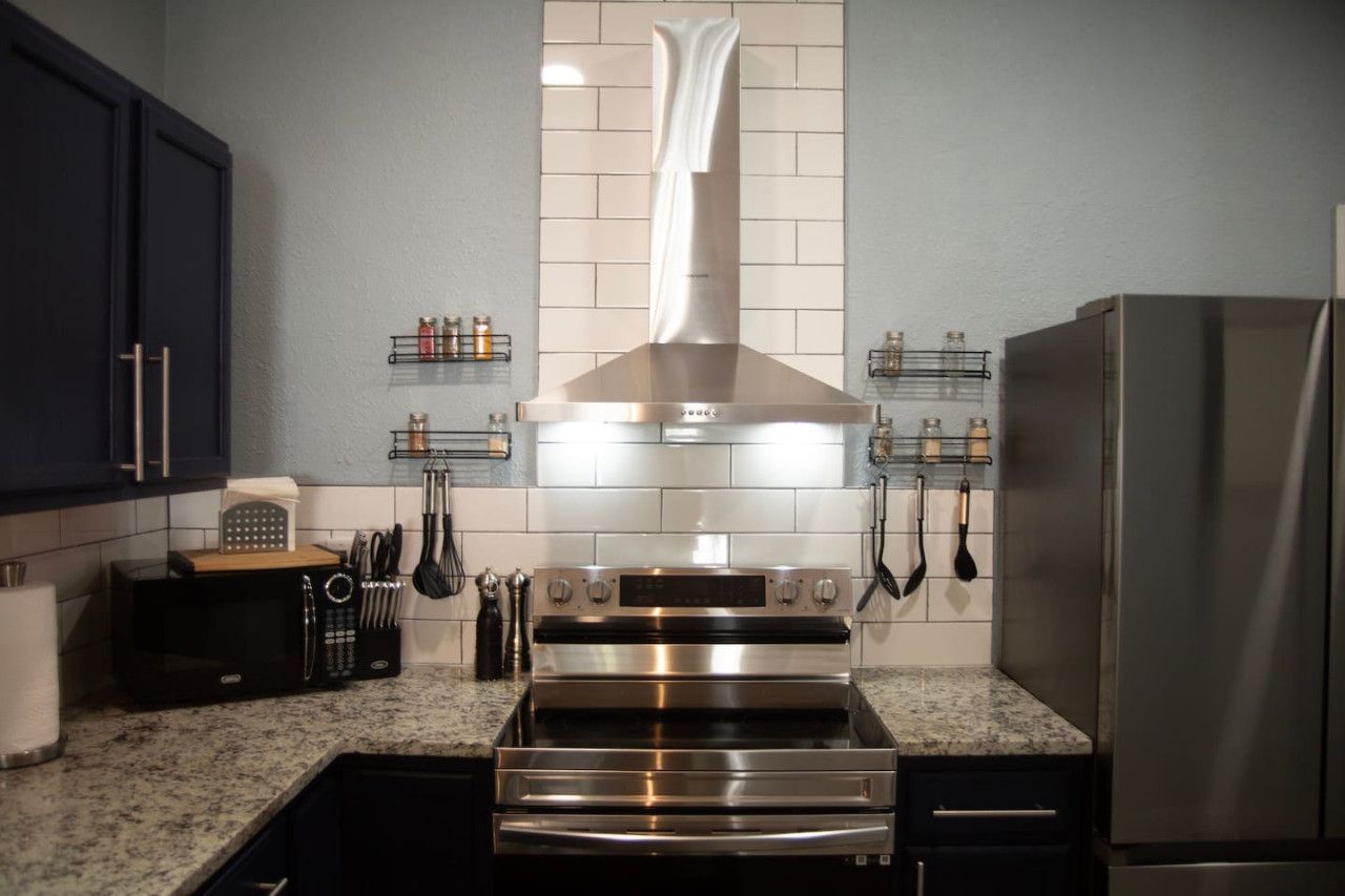 A kitchen with a stainless steel range hood, oven, and refrigerator.