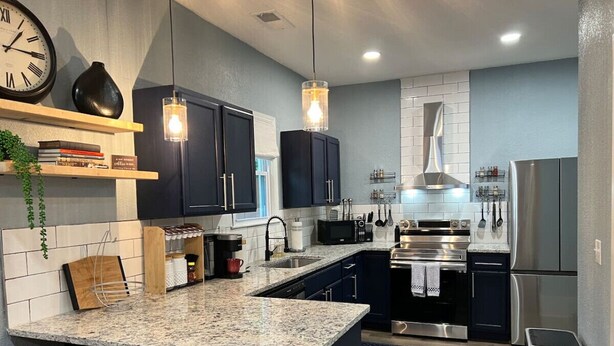 A modern kitchen with dark cabinets, granite countertops, stainless steel appliances, and pendant lighting. - Lovely Pet Frendly Home by Sherman (Boiling Springs)