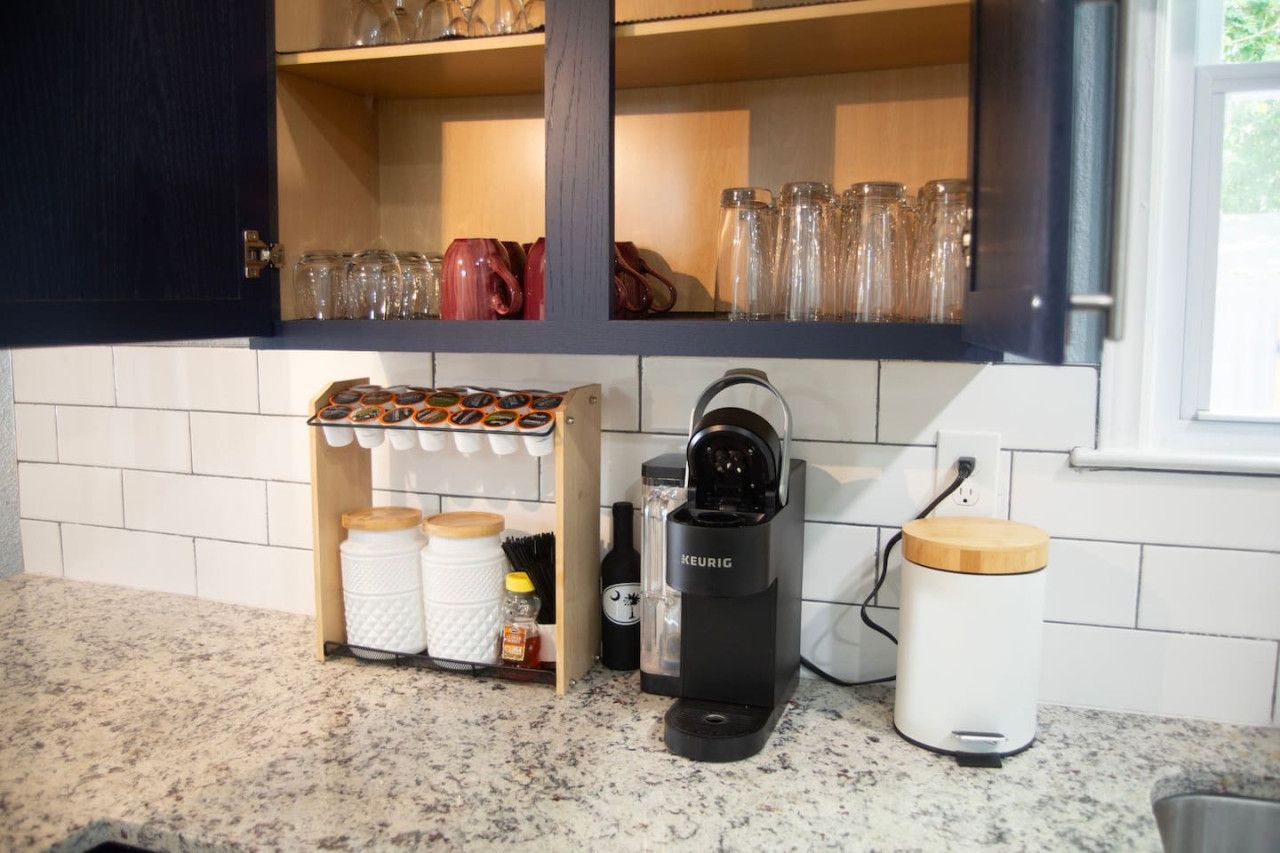 A kitchen with a coffee maker, jars, and a spice rack.