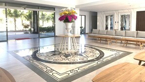 A spacious lobby with a central white vase of flowers, a patterned floor, a sofa, and a wooden bench. - BO BIEN VANG HOTEL (Tan Thanh)