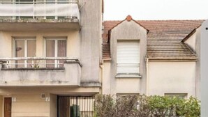 Ein zweistöckiges Gebäude mit einem Balkon im oberen Stockwerk und einer Garagentür im unteren Stockwerk.