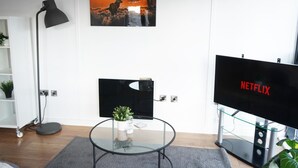 A modern living room with a flat-screen TV, a glass coffee table with a plant, and a painting of a deer on a wall. - Apartment - Sleeps 4 - Pet friendly - WiFi (Sheffield)