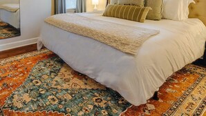 Ein Schlafzimmer mit einem großen Bett, einem Deckenventilator und einem gemusterten Teppich.