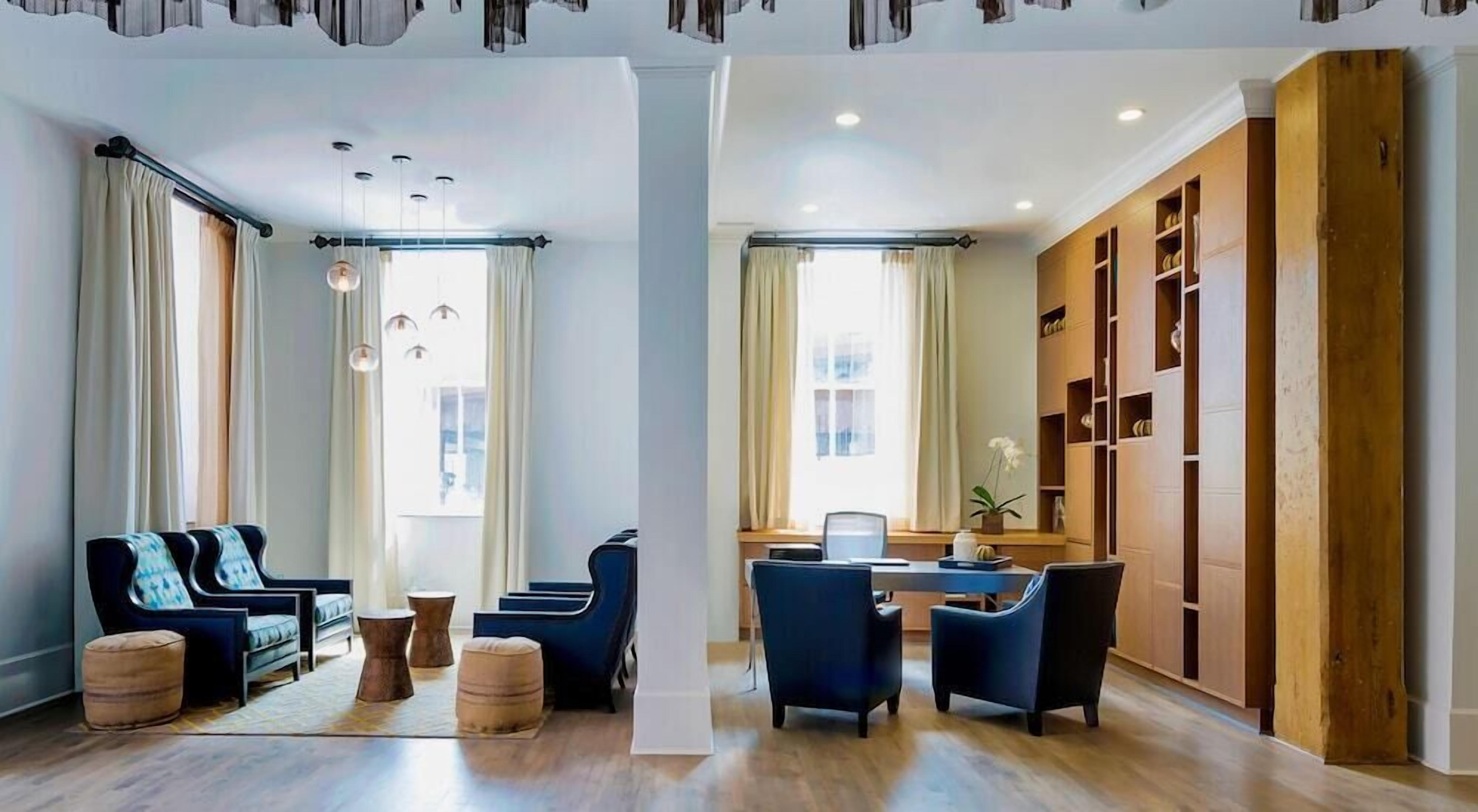 A spacious living area with a modern sofa set, a dining table with chairs, and a wooden bookshelf.