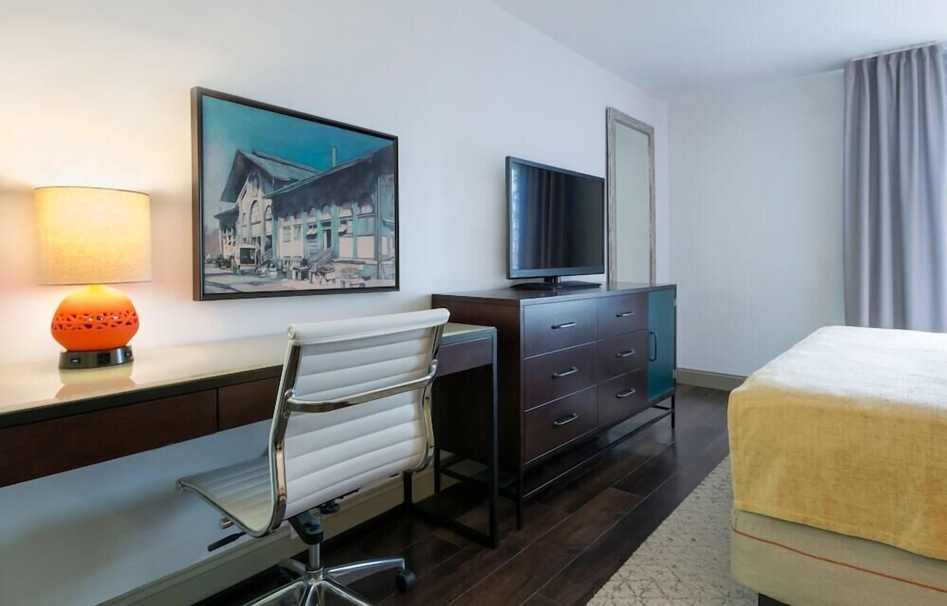 Habitación de hotel con escritorio, silla, televisión y cama.