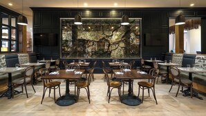 A restaurant with dark wood paneling, stone wall art, and multiple dining tables and booths. - 1-Bedroom Suite at a 4⭐️ Hotel (Savannah)