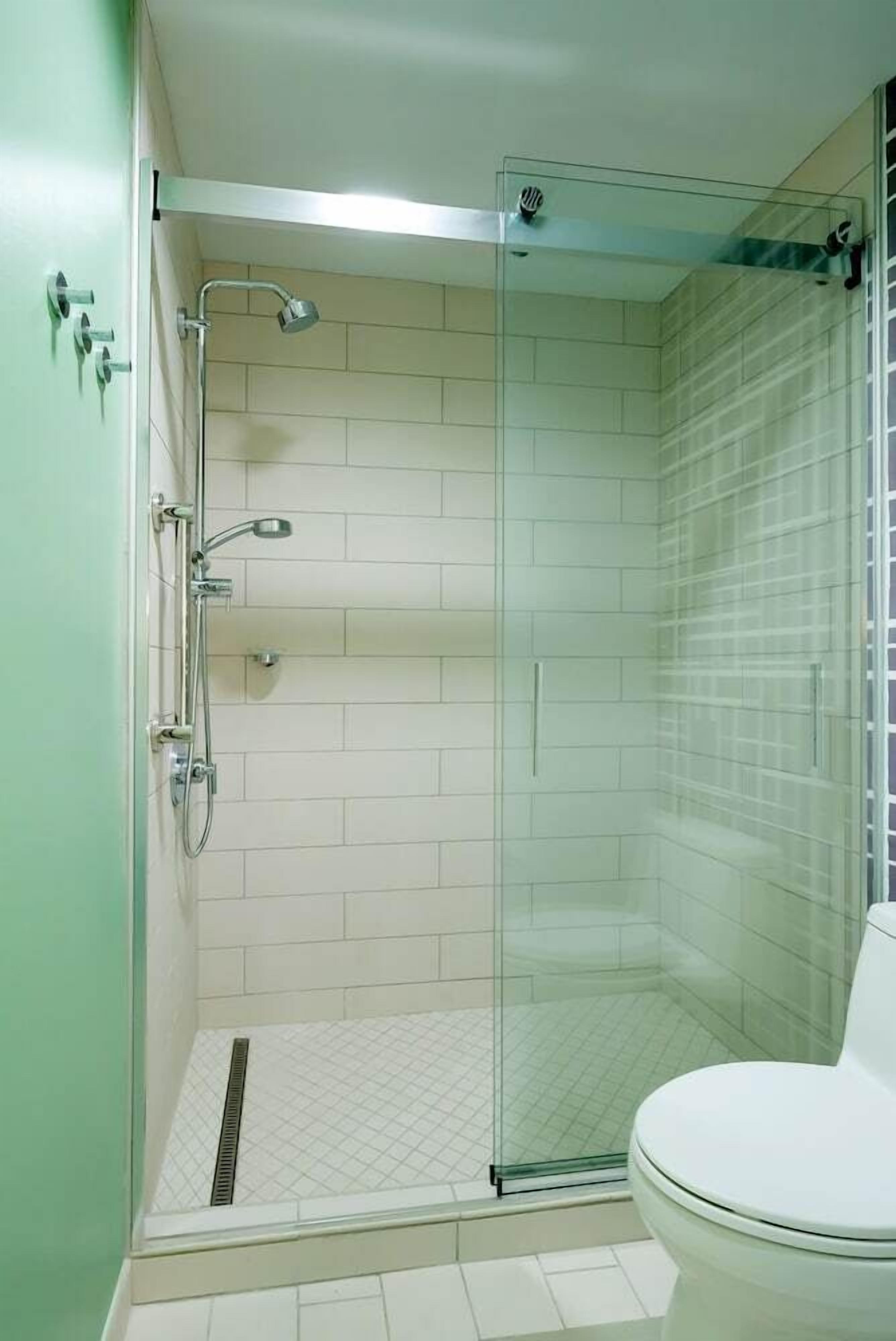 A glass-enclosed shower with a toilet to the right.