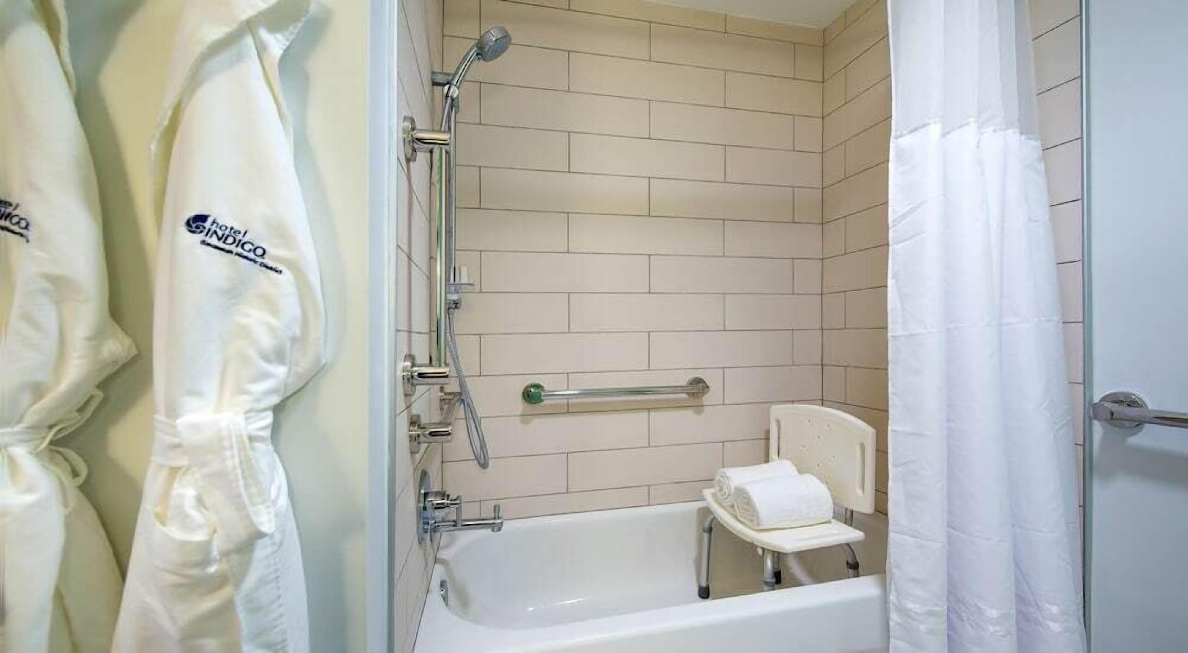 A bathroom with a bathtub, a shower, and a toilet. There are towels and a robe hanging on the wall.