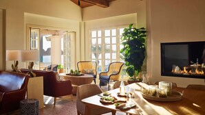 A spacious living room with a fireplace, comfortable seating, and large windows.