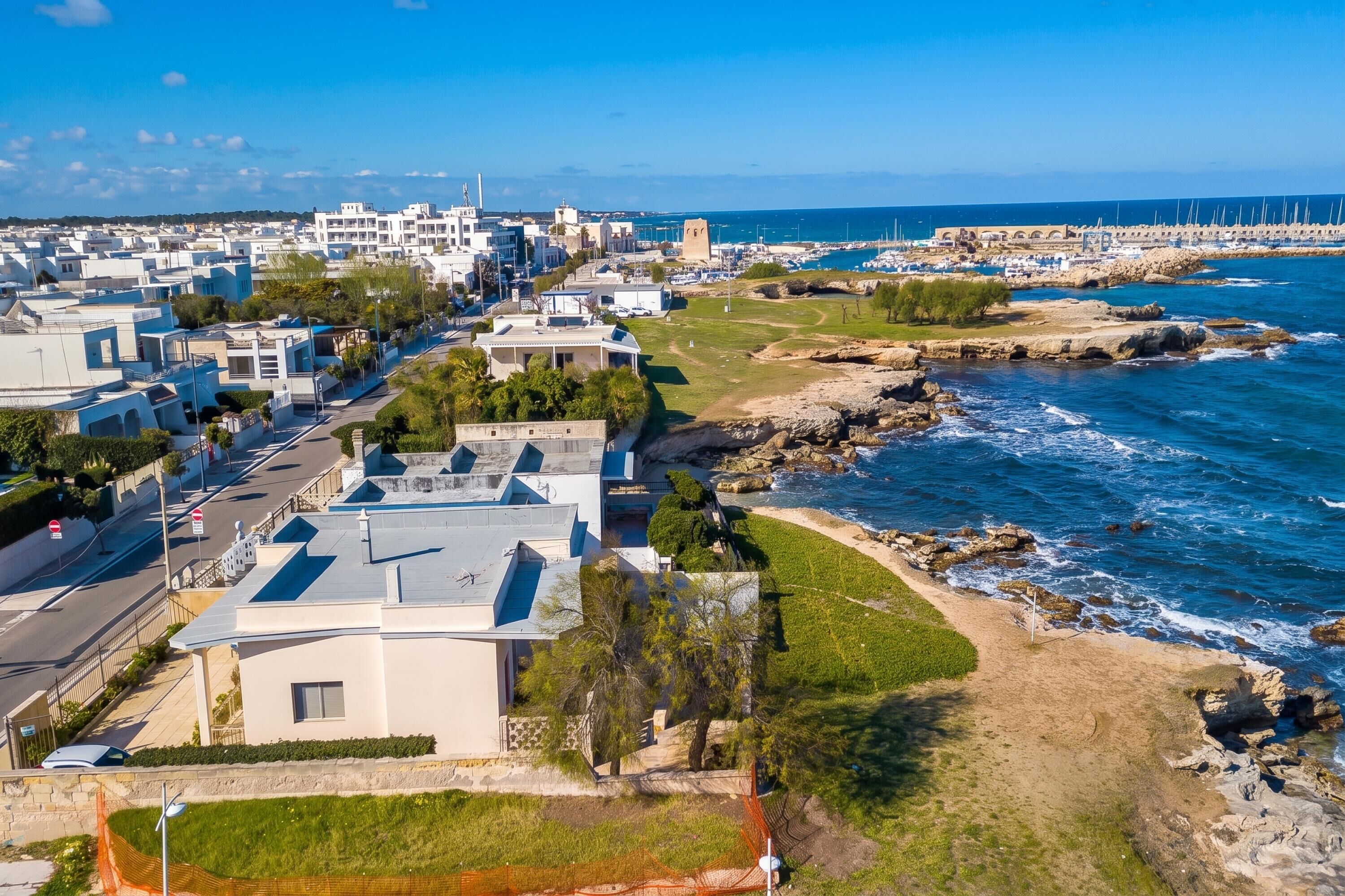 A coastal town with modern buildings, a rocky shoreline, and a marina.