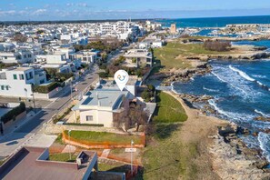 An aerial view of a coastal residential area with modern buildings, a marina, and rocky coastline. - Villa Grazia on the seaside, Melendugno, Italy (Melendugno)