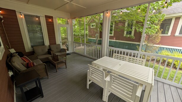 A covered porch with a sofa, chairs, and a table.