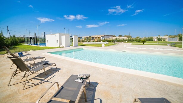 A swimming pool with lounge chairs and a small poolside table. - Villa Cristal Pool and Padel, Galatina, Italy (Galatina)
