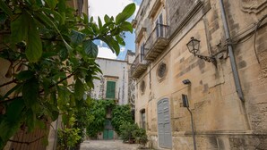 A narrow cobblestone street flanked by historic buildings with green shutters and a potted plant. - Villa Cristal Pool and Padel, Galatina, Italy (Galatina)