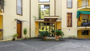 A courtyard with a building entrance, potted plants, and a no parking sign. - Relais Vittoriale (Gardone Riviera)