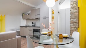Una cocina moderna con armarios blancos, una mesa de comedor de vidrio y una lámpara colgante.
