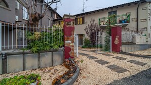 Zona residencial con entrada porticada, un árbol y un edificio con balcón.
