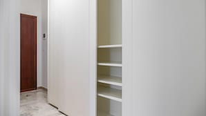 Ein Flur mit einer Holztür und einem weißen Schrank mit Regalen.