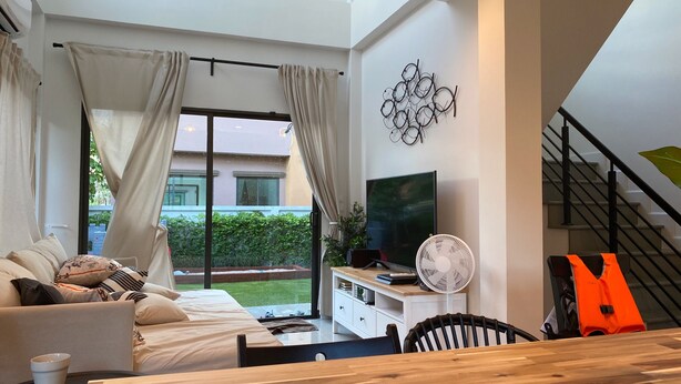 A modern living room with a sofa, a coffee table, a TV, and a staircase. - Castello Di Mare (Cha-am)