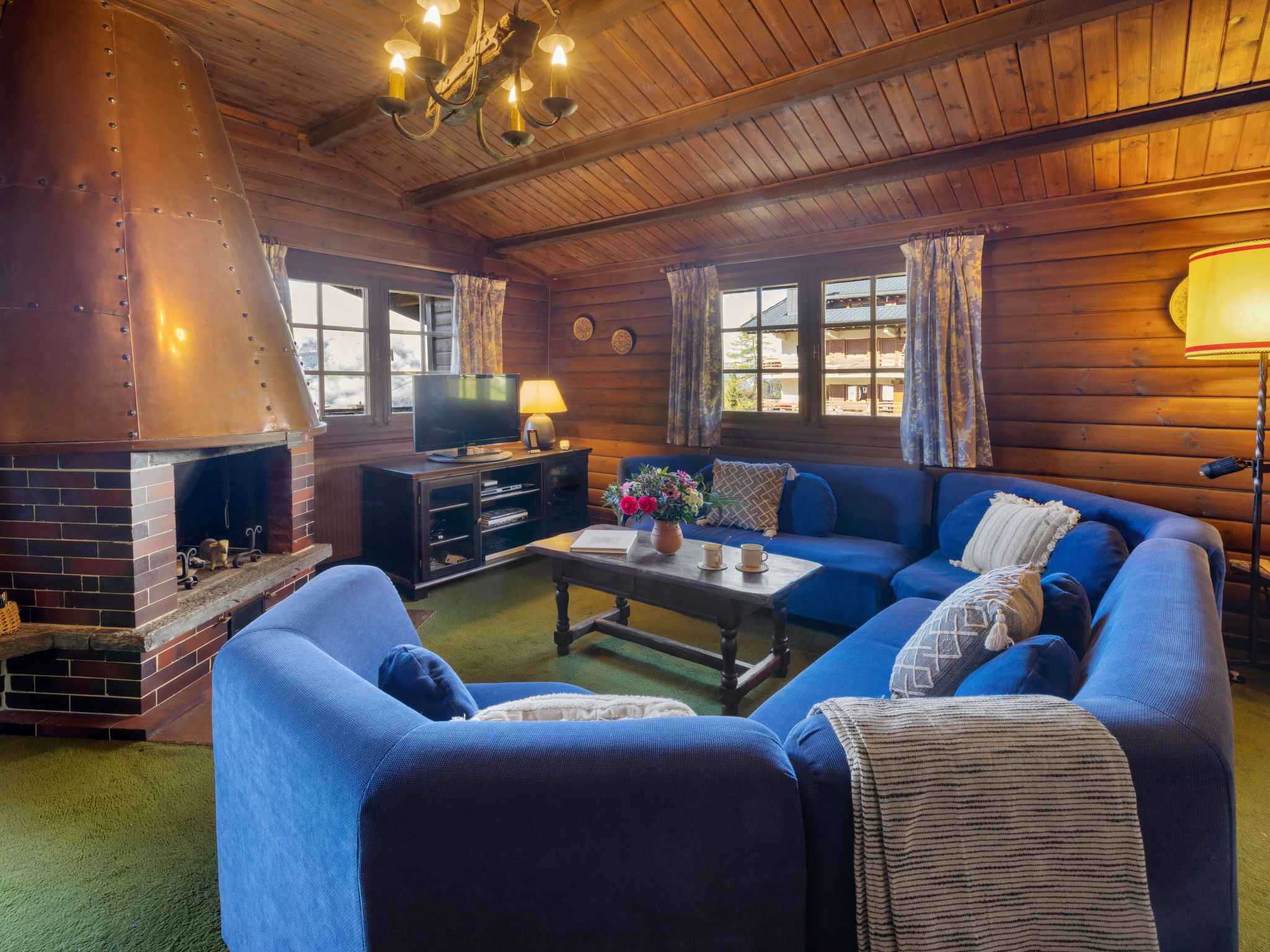 A cozy living room with a fireplace, blue sofa, and a television.