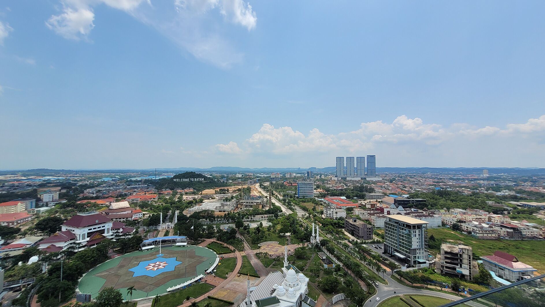 A cityscape with a prominent sports field, a mosque, and modern buildings.