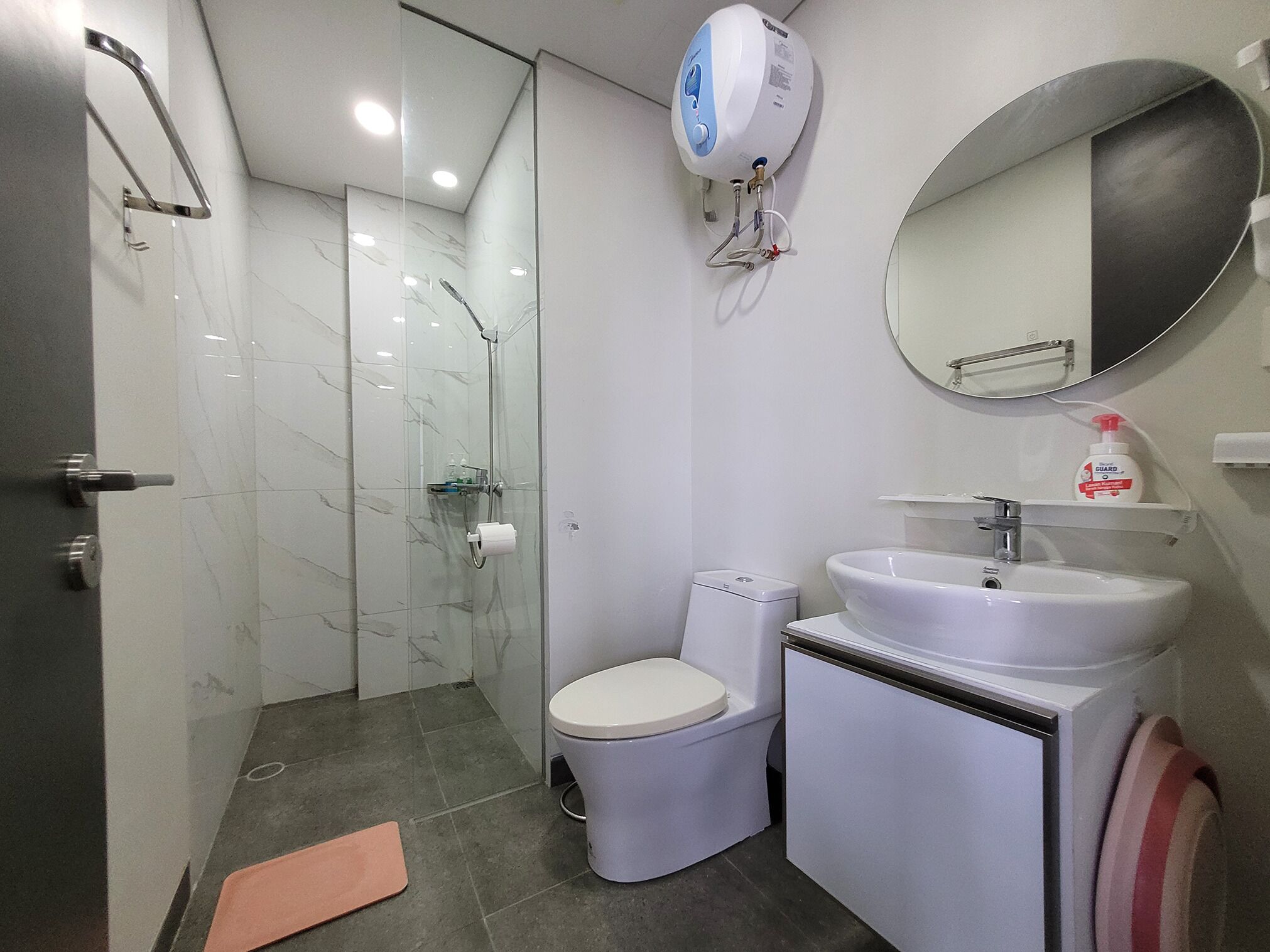 A modern bathroom with a glass-enclosed shower, a toilet, a sink, and a mirror.