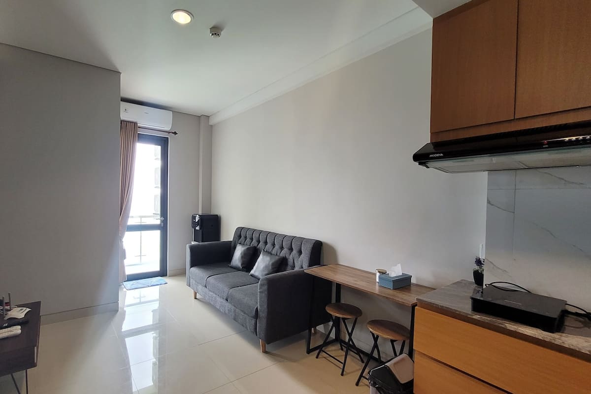 Eine moderne Wohnung mit grauem Sofa, einem Holzesstisch und einer Küchenzeile.
